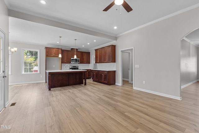 kitchen featuring hanging light fixtures, light hardwood / wood-style flooring, a center island with sink, appliances with stainless steel finishes, and ornamental molding