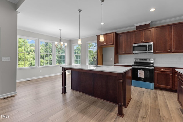 kitchen with sink, stainless steel appliances, light hardwood / wood-style flooring, an island with sink, and a chandelier