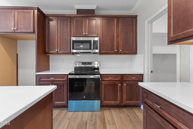 kitchen with tasteful backsplash, ornamental molding, appliances with stainless steel finishes, and light hardwood / wood-style flooring