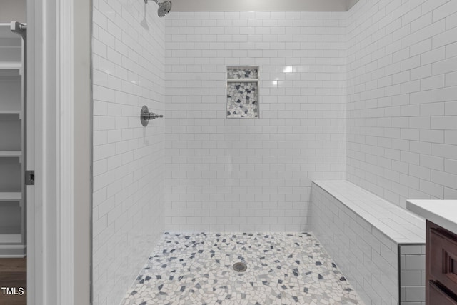 bathroom with tiled shower and vanity