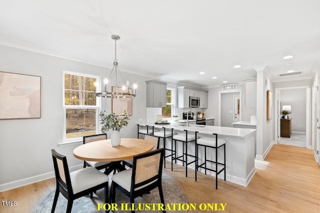 dining room with an inviting chandelier, sink, crown molding, and light hardwood / wood-style floors