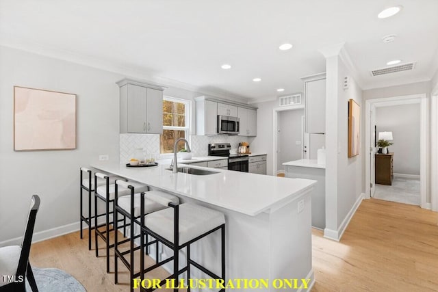 kitchen with stainless steel appliances, kitchen peninsula, sink, and a breakfast bar area