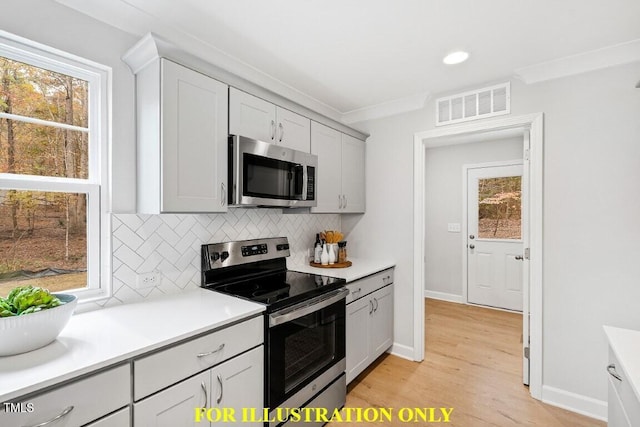 kitchen featuring decorative backsplash, light hardwood / wood-style flooring, ornamental molding, and appliances with stainless steel finishes