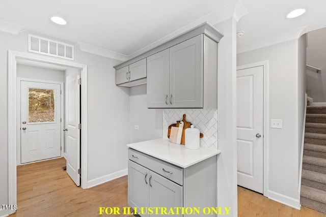 kitchen featuring backsplash, ornamental molding, light wood-type flooring, and gray cabinetry