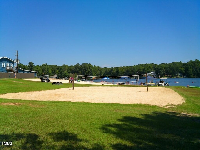 surrounding community with a water view, volleyball court, and a lawn