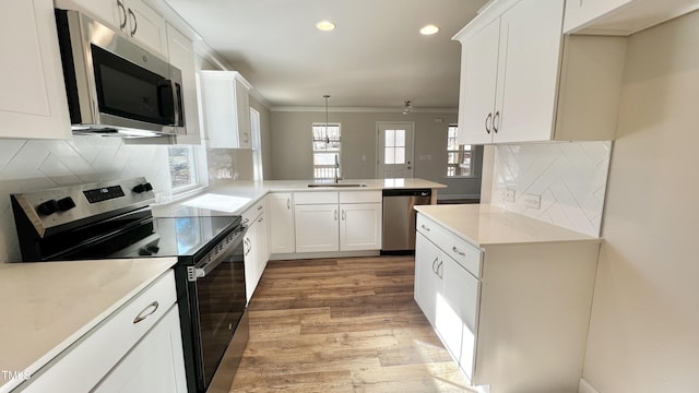 kitchen with white cabinetry, stainless steel appliances, tasteful backsplash, decorative light fixtures, and kitchen peninsula