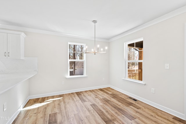 unfurnished dining area featuring a chandelier, wood finished floors, visible vents, baseboards, and ornamental molding