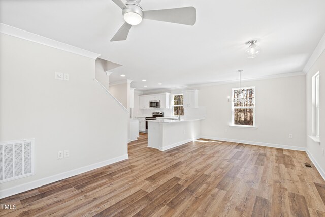 unfurnished living room featuring baseboards, light wood-type flooring, visible vents, and crown molding