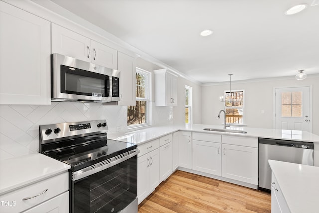 kitchen with appliances with stainless steel finishes, light countertops, a sink, and decorative backsplash