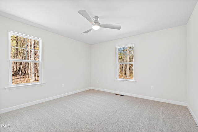 carpeted empty room with ceiling fan, visible vents, and baseboards