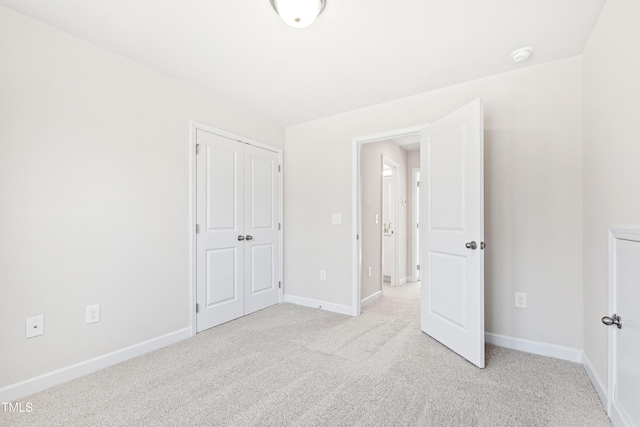 unfurnished bedroom featuring baseboards, a closet, and light colored carpet