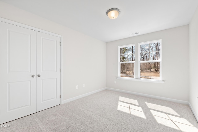 unfurnished bedroom featuring carpet floors, a closet, visible vents, and baseboards