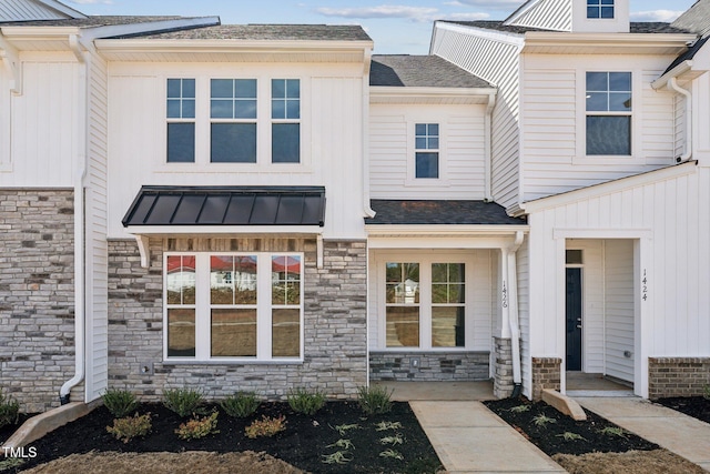 townhome / multi-family property with a shingled roof, stone siding, metal roof, and a standing seam roof