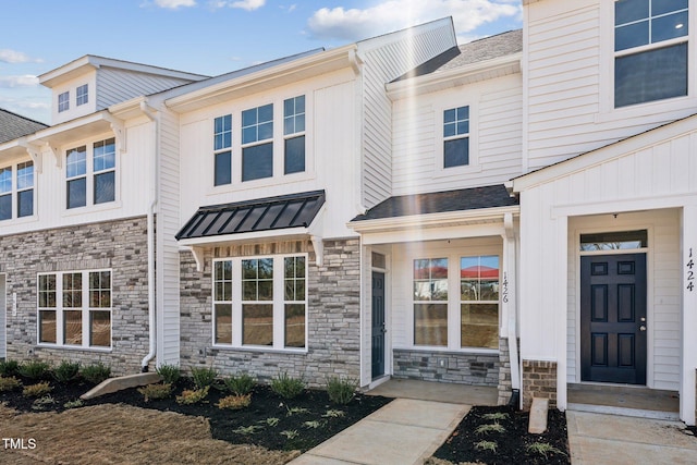 view of front of house with metal roof, stone siding, a standing seam roof, and roof with shingles