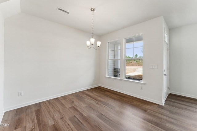 unfurnished dining area featuring baseboards, visible vents, a chandelier, and wood finished floors