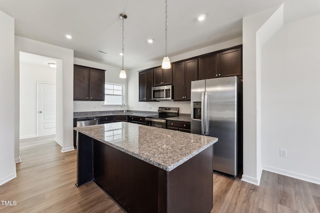 kitchen featuring a kitchen island, a sink, dark brown cabinets, appliances with stainless steel finishes, and light wood-type flooring