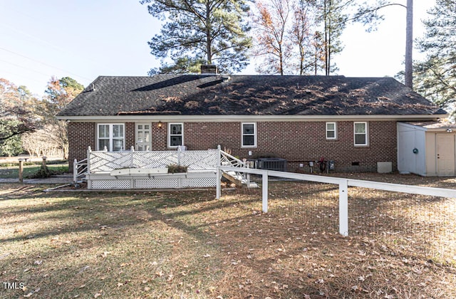 view of front facade featuring a shed, a deck, a front yard, and central AC