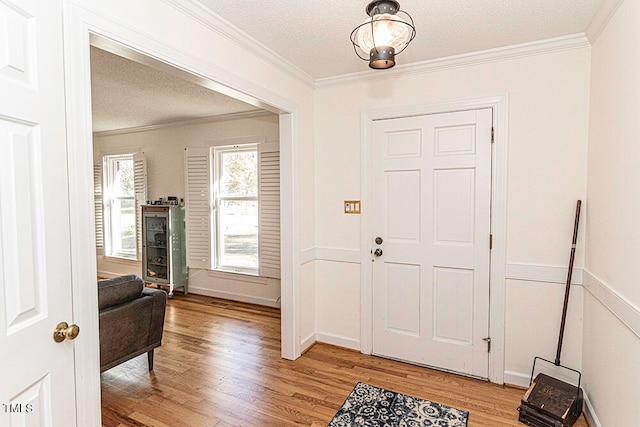 entryway featuring a textured ceiling, light hardwood / wood-style floors, and crown molding