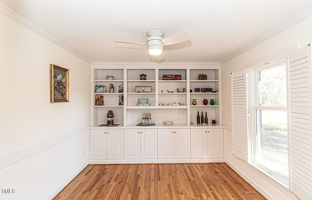 empty room with a textured ceiling, light wood-type flooring, ceiling fan, and crown molding