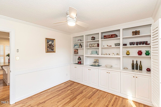 interior space with a textured ceiling, ceiling fan, crown molding, and light hardwood / wood-style flooring