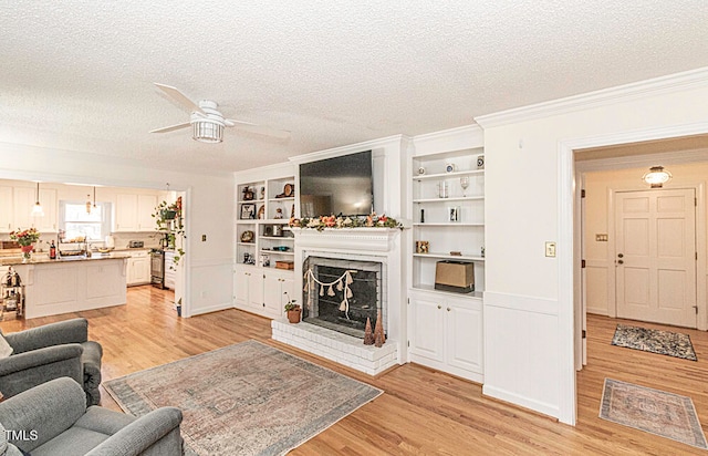 living room with a fireplace, a textured ceiling, light hardwood / wood-style flooring, and ceiling fan