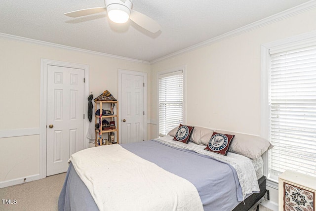 carpeted bedroom with ceiling fan, ornamental molding, and a textured ceiling