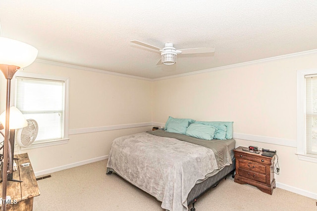 bedroom with a textured ceiling, light colored carpet, ceiling fan, and crown molding