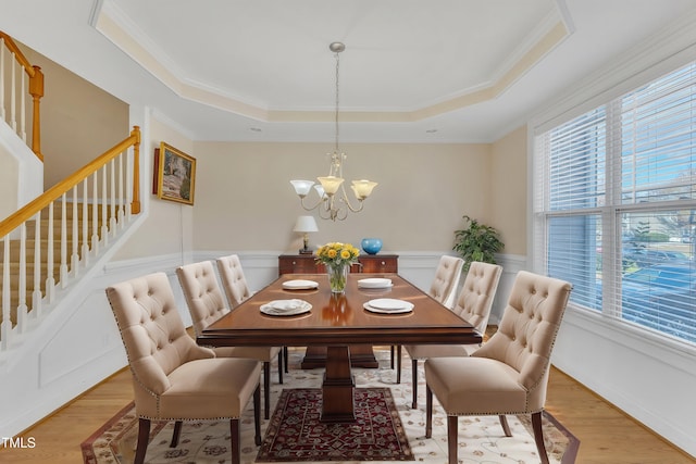 dining area featuring plenty of natural light, ornamental molding, a tray ceiling, and light hardwood / wood-style flooring