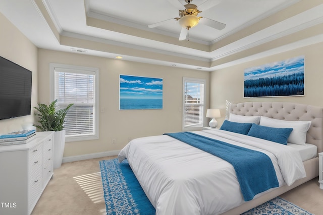 bedroom featuring light carpet, a tray ceiling, multiple windows, and ceiling fan