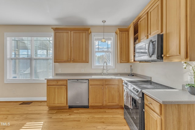 kitchen featuring sink, stainless steel appliances, pendant lighting, light hardwood / wood-style floors, and light brown cabinetry