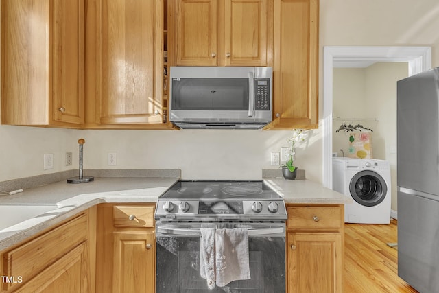 kitchen with washer / dryer, light wood-type flooring, and stainless steel appliances