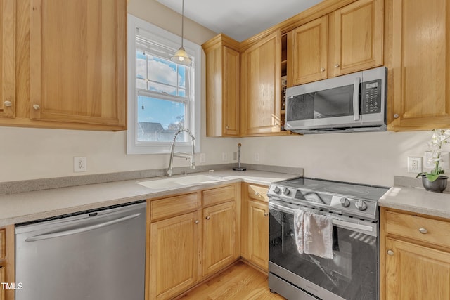 kitchen featuring sink, hanging light fixtures, light brown cabinetry, appliances with stainless steel finishes, and light wood-type flooring