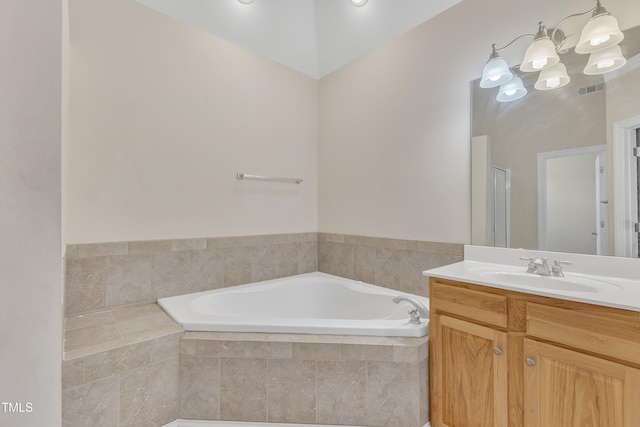 bathroom featuring a chandelier, vanity, and a relaxing tiled tub