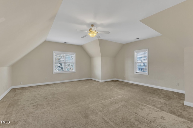 additional living space with light colored carpet, vaulted ceiling, a wealth of natural light, and ceiling fan