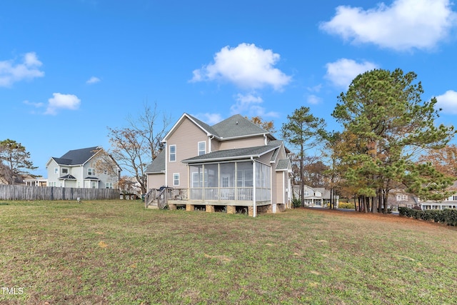 rear view of house featuring a yard, a deck, and a sunroom