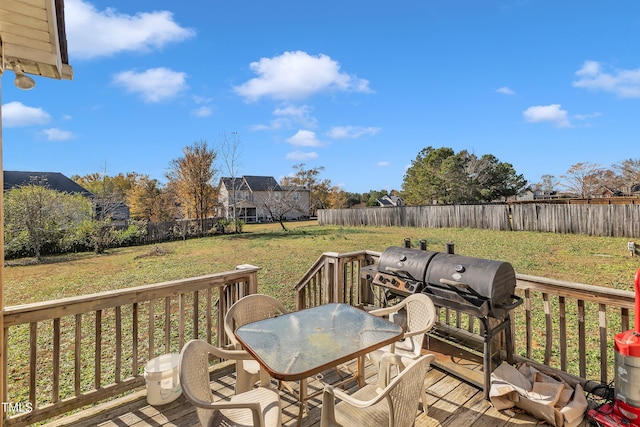 wooden terrace with a lawn and area for grilling