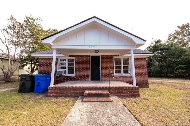 bungalow with cooling unit, covered porch, and a front lawn