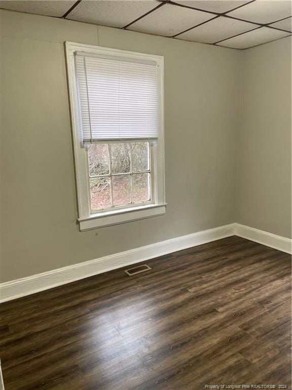 unfurnished room featuring a paneled ceiling and dark hardwood / wood-style floors