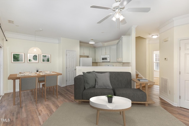 living room featuring ceiling fan, ornamental molding, and dark hardwood / wood-style flooring