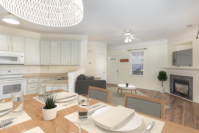 dining room with crown molding, sink, hardwood / wood-style floors, and ceiling fan