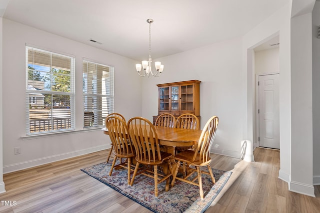 dining area featuring light hardwood / wood-style floors and a notable chandelier