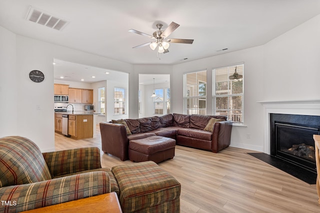 living room featuring ceiling fan, sink, and light hardwood / wood-style floors