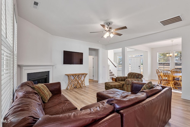 living room featuring ceiling fan with notable chandelier and light hardwood / wood-style floors