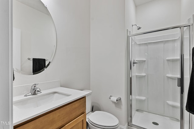 bathroom featuring vanity, toilet, and a shower with door