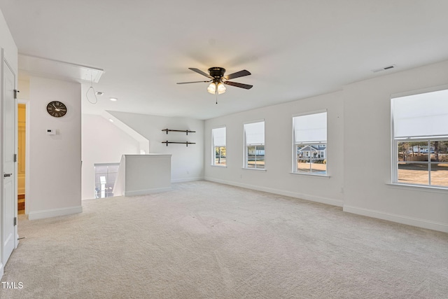 unfurnished living room with ceiling fan, light colored carpet, and a wealth of natural light