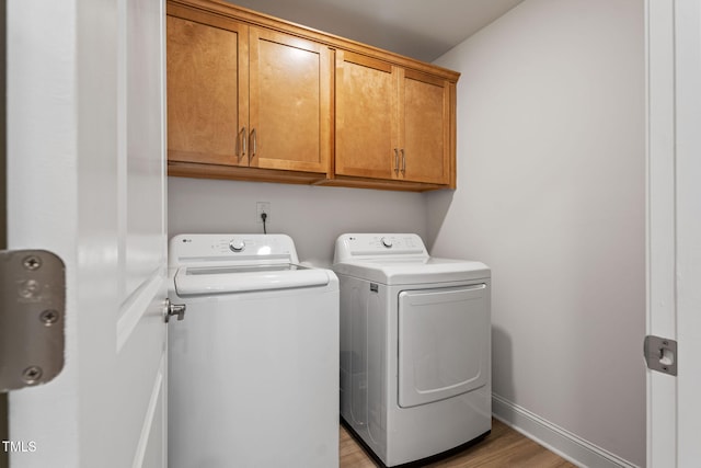 laundry room featuring cabinets, light hardwood / wood-style flooring, and washing machine and clothes dryer