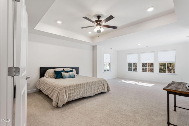 bedroom featuring light carpet, a tray ceiling, and ceiling fan