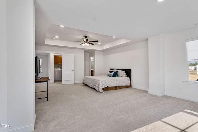 carpeted bedroom with washer / clothes dryer, ceiling fan, and a tray ceiling