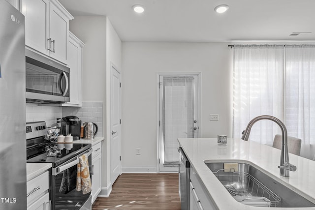 kitchen with tasteful backsplash, stainless steel appliances, dark wood-type flooring, sink, and white cabinets