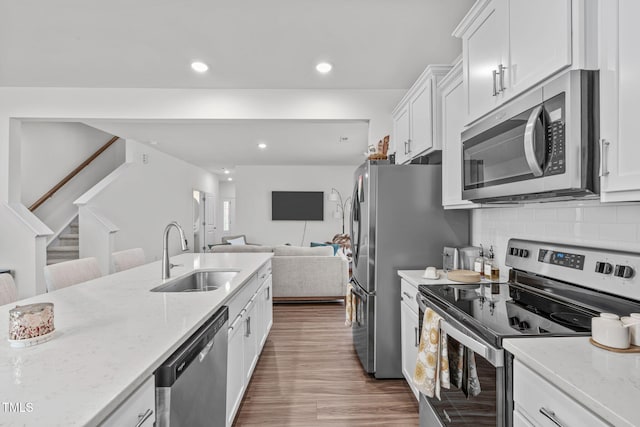 kitchen with light stone countertops, sink, white cabinets, and stainless steel appliances